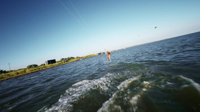 Woman kiteboarding across water with red kite in slow motion