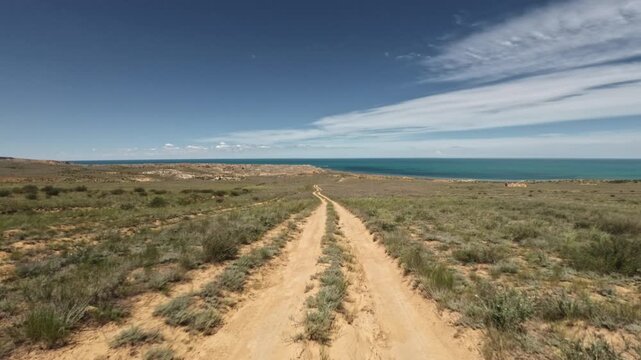 Camera moves forward along dirt road toward water