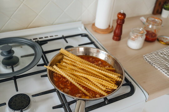Cooking Italian pasta boiling in a stainless steel pot on a modern kitchen stove, home culinary preparation concept