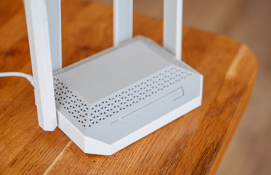 Modern wireless Wi-Fi internet router standing on a wooden table, high-speed home network and telecommunication concept