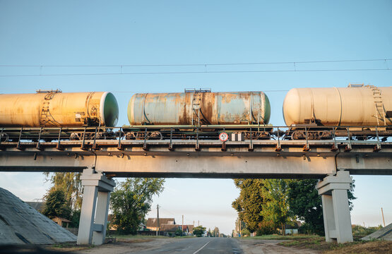 Three freight train cars moving across a tall concrete viaduct bridge, cargo transportation and logistics infrastructure