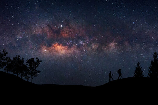 Landscape with Milky Way. Night sky with stars and silhouette of a standing happy man on the mountain, Success or winner, leader concept. High iso with Noise.