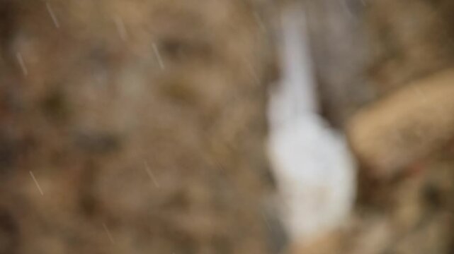 Snowflakes fly sideways in slow motion and shallow depth of field