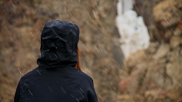 Woman wearing black hooded jacket standing in snow
