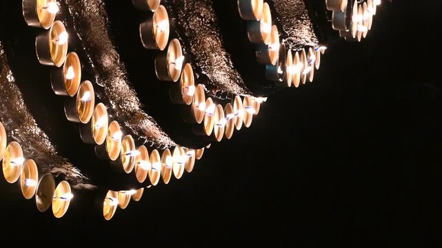 Rows of Lit Prayer Candles in a Dark Temple