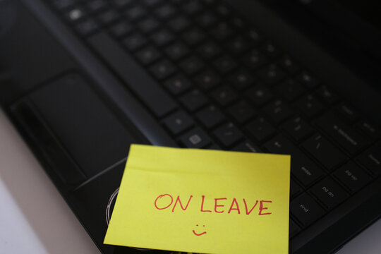 On leave&mdash;specifically, annual leave for an employee. A sticky note reading "ON LEAVE" is placed on the keyboard, signaling to the workspace that the person in question is currently away from work.