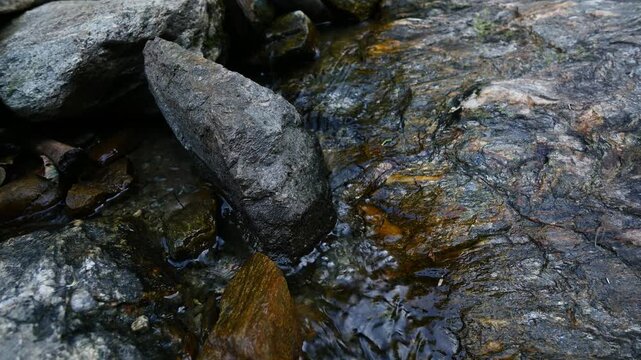 Clear stream water flowing over rocks in nature