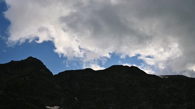 Dark mountain range silhouette against moving clouds