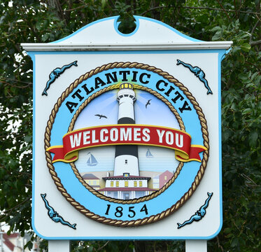 Colorful Atlantic City welcome sign featuring a central lighthouse emblem framed by braided rope, sailboats and seagulls with the year 1854, evoking coastal history, seaside tourism and summer charm.