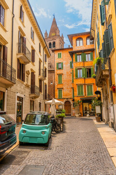 Italy Verona old town. Narrow Italian street brightly orange color Houses building facade and green shutters. Travel background.