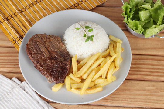 Prato com arroz, batata frita e carne