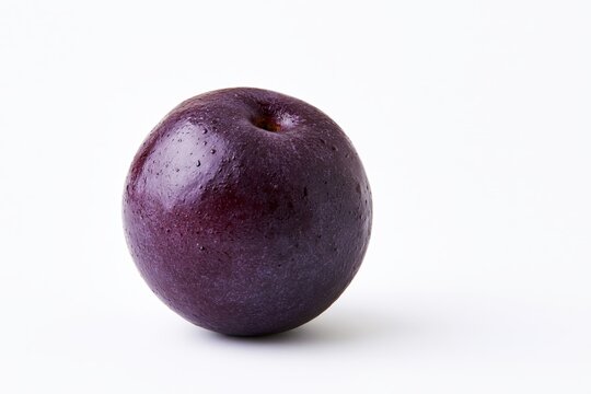 Single ripe plum with glossy skin and tiny water droplets resting on a clean white surface under soft directional lighting, showcasing vibrant deep purple hue and natural texture