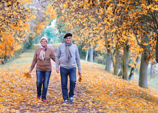 Happy Couple Laughing and Walking Together in a Colorful Autumn Alley