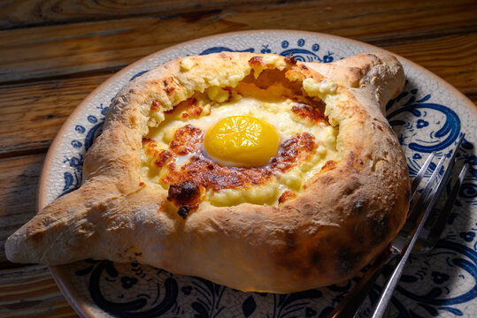 Adjarian Khachapuri (Adjaruli Khachapuri) famous Georgian boat shaped cheese bread topped with a raw egg yolk and butter from the coastal Adjara region on the Black Sea
