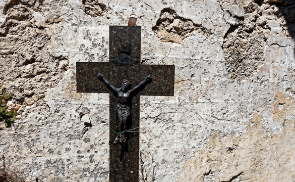 Old crucifix on a stone wall weathered by time, in Provence, France.