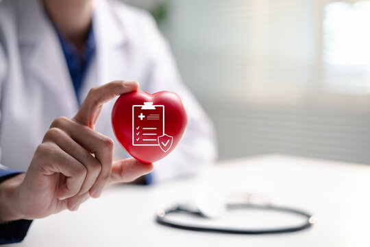 A doctor holds a red heart with a health insurance protection icon. The image represents medical coverage, policy approval, patient safety, preventive care and financial security for families.