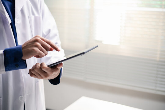 A doctor uses a tablet for digital healthcare data management. The image represents electronic medical records, clinical workflow, mobile technology and efficient hospital administration.