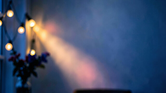 Blurred cozy indoor reading nook illuminated by warm glowing string lights on navy blue wall for serene evening banner background