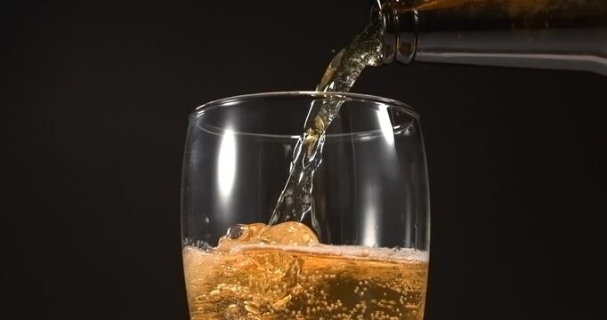 Beer pouring from glass bottle into mug in slow motion