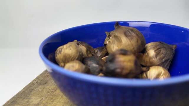 Fermented single clove garlic for herbal medicine in a blue bowl