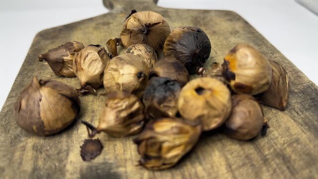 Single clove black garlic on wooden board for herbal health use