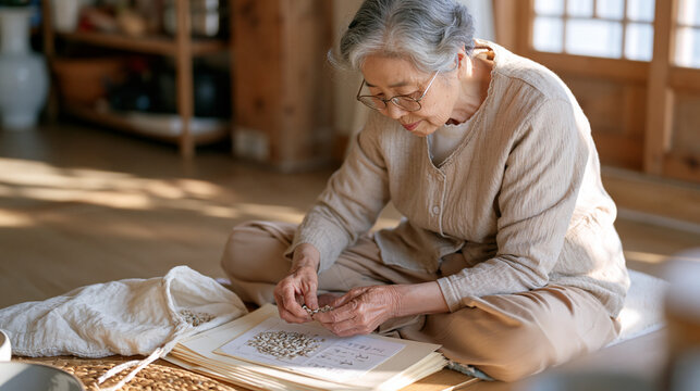 A Korean grandmother sitting cross legged on a wooden floor carefully selecting and sorting dried bean seeds from a muslin bag into paper envelopes for next season, seed bank