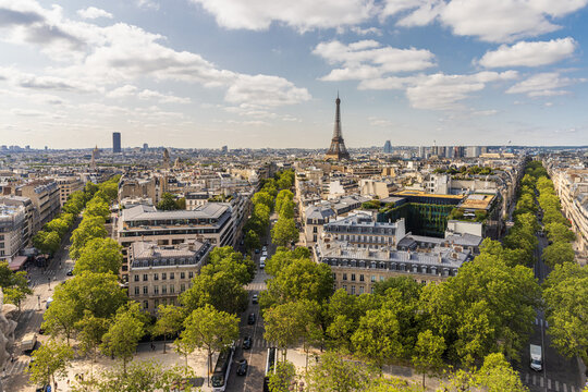 A wide, high-angle view captures the expansive Paris skyline and the iconic Eiffel Tower