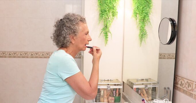 Mature woman applying lipstick
