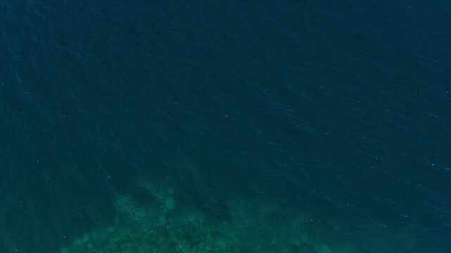 Aerial view of the clear turquoise waters and rocky shoreline of Diaporos Island, located in Halkidiki, Macedonia, Greece