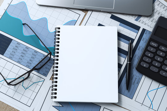 Blank spiral notebook, pen, calculator, laptop, and business charts arranged on a modern office desk for workspace planning and branding. 3D Rendering