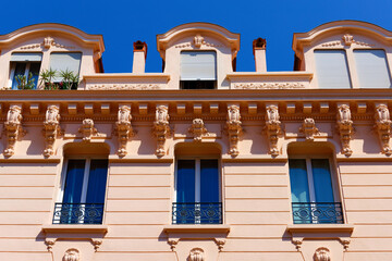 Pink Belle Epoque building facade with carved corbels and wrought-iron balconies, Cannes French Riviera, France. © kovalenkovpetr