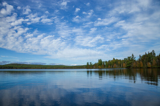 Beautiful calm blue northern Minnesota lake with pines on the shore and clouds above