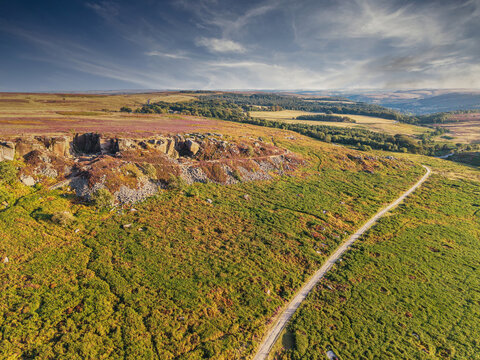 Beautiful drone landscape image view over Burbage South Edge in Peak District during Summer heather sunset