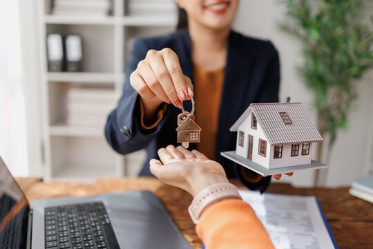 Real estate agent giving house keys to client, representing home ownership, property investment, mortgage agreement, buying a new house, and successful business deal
