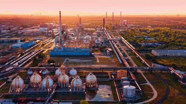 Spherical gas containers in chemical refinery complex. Metal pressure spheres reflect in surface water near tall stacks during warm evening.