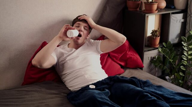 Sick guy with cold, flu or virus illness with cough and running nose lying in bed and using tissues. Sneezing ill guy at home. Man and health