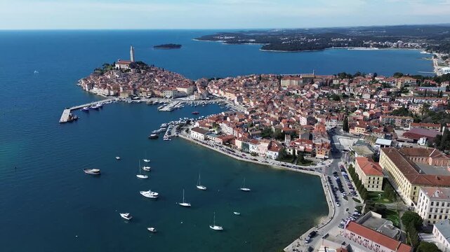 Aerial view of Rovinj historic old town in Croatia, featuring red tiled rooftops, St. Euphemia Church, marina, boats and the beautiful Adriatic coastline.
