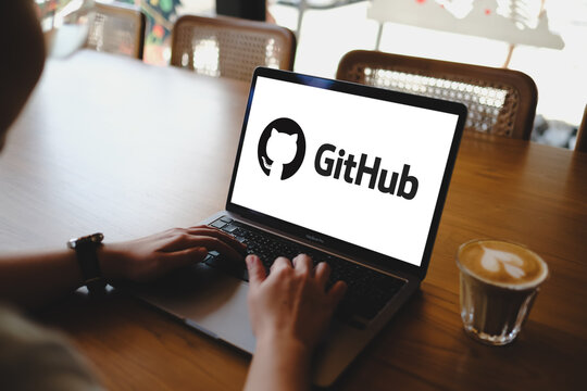 Bangkok, Thailand. September 30, 2026; A person typing on laptop computer displaying GitHub software development platform logo on screen at cafe table.