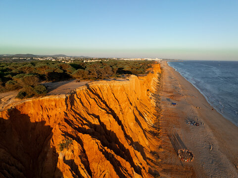Cliffs and beach at sunset with people gathered along the shoreline in Albufeira, Portugal