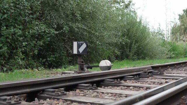 Close-up view of a railway switch mechanism beside train tracks in a green rural landscape