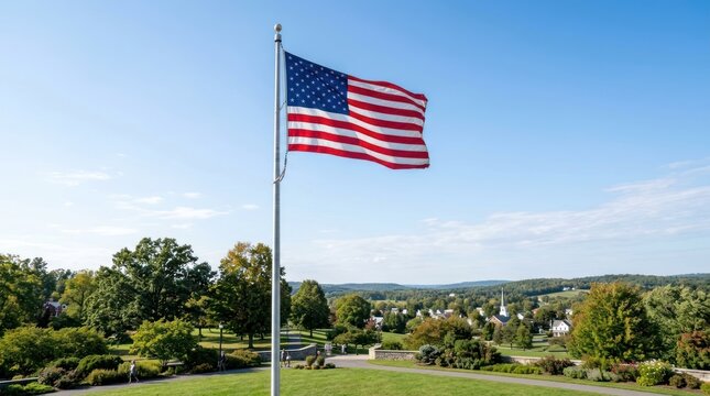 A flagpole with an American flag waving in the wind against a clear blue sky.