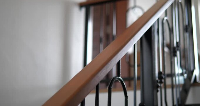 Close up of wooden handrail with wrought iron balusters on staircase