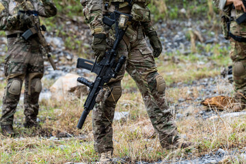 Obraz premium Soldiers in military gear train with weapons in a forested area during daytime