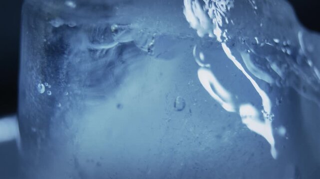 Ice cube in macro view showing frozen bubbles and a cool blue, natural texture. Stock video, background loop, ideal for drink or food products, recipes, night bar events etc. 
