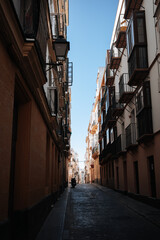 Fototapeta premium Narrow street with tall buildings and balconies under a clear blue sky