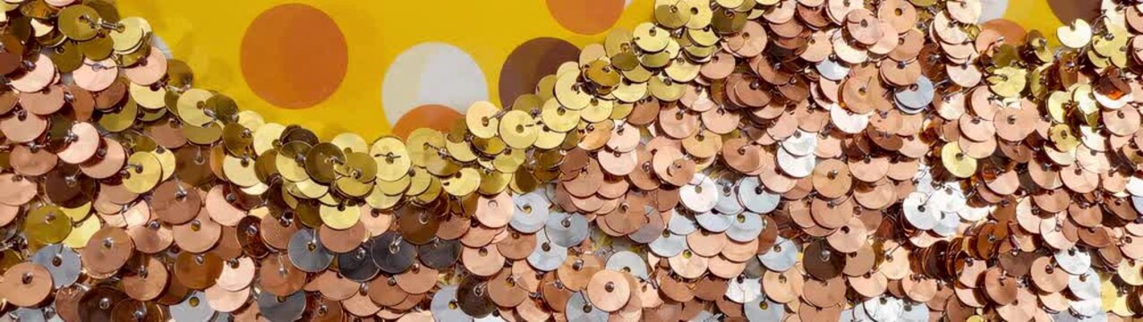 Luxury fashion and celebration background gold and bronze sequins flowing over a polka dot pattern festive party texture and glamour.