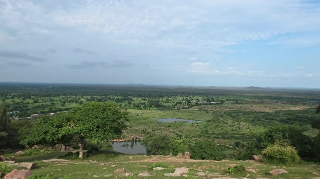 Elevated viewpoint reveals an expansive verdant valley under soft clouds.