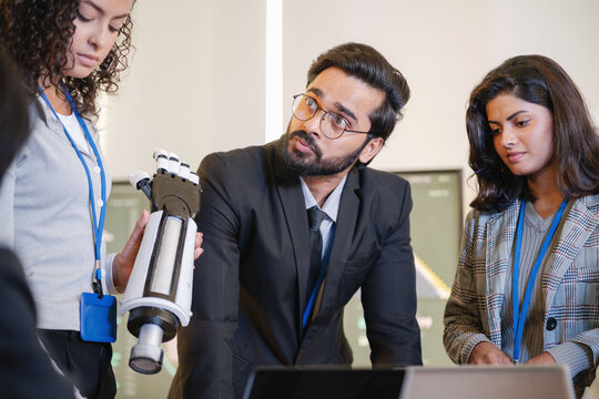 Technology professionals examining a robotic prototype and discussing its design and development in a modern research and engineering environment.