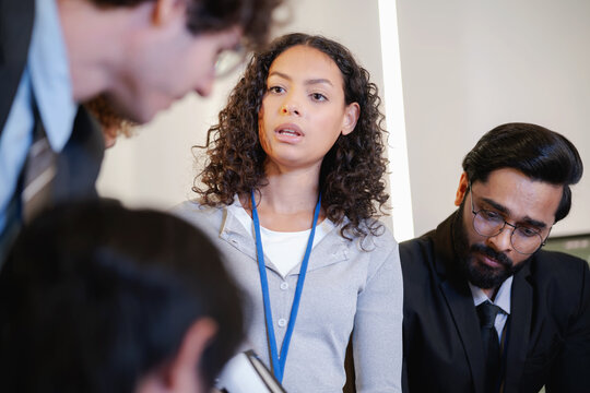Female technology professional speaking to colleagues during a collaborative discussion in a modern research and development workplace.