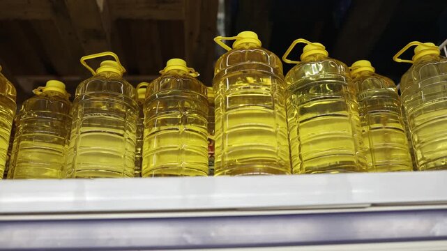 Large bottles of vegetable cooking oil stand in rows on store shelf showing golden edible oil in bulk containers for frying baking and everyday household food preparation